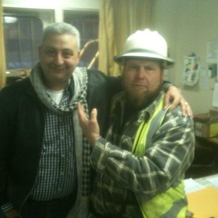 Billy Brown with a crew member in a hard hat and safety vest in the ship's office