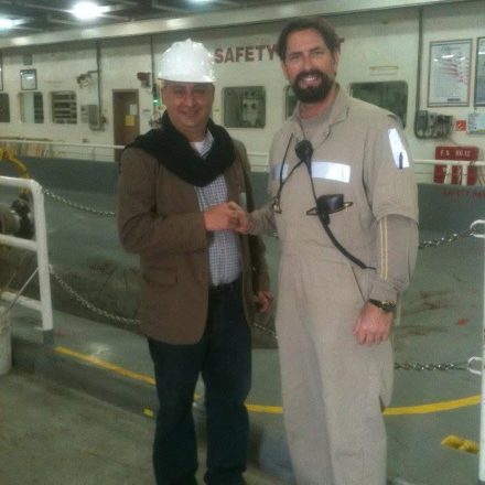 Billy Brown in a hard hat shaking hands with an officer on the vehicle deck