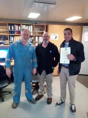 Charly Brown representative with a ship's officers in the ship's office